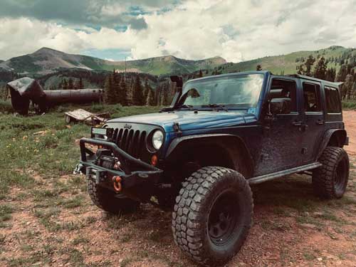 Photo of Jeep in front of mountain scene with cloudy sky