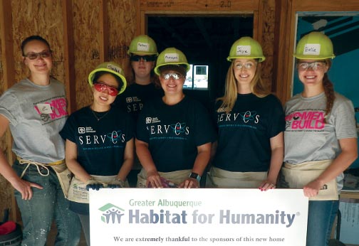 Habitat for Humanity volunteers pose with sponsorship sign for Habitat for Humanity