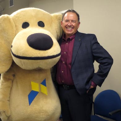 SLFCU’s former President and CEO Robert Chavez and Sandy the Lab pose for a photo