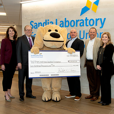 SLFCU and Mimbres School leadership holding $200,000 check with Sandy the Lab